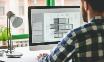 Male architect working on a building plan on a computer.