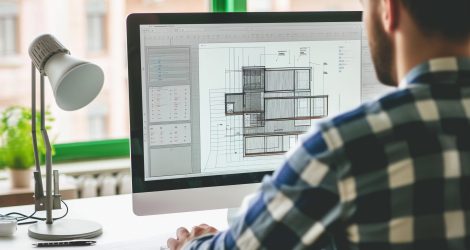 Male architect working on a building plan on a computer.