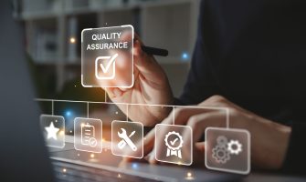 Hand of businessman holding a pen pointing to Quality Assurance icon for service guarantee on laptop screen,  Standards control and certification concept.